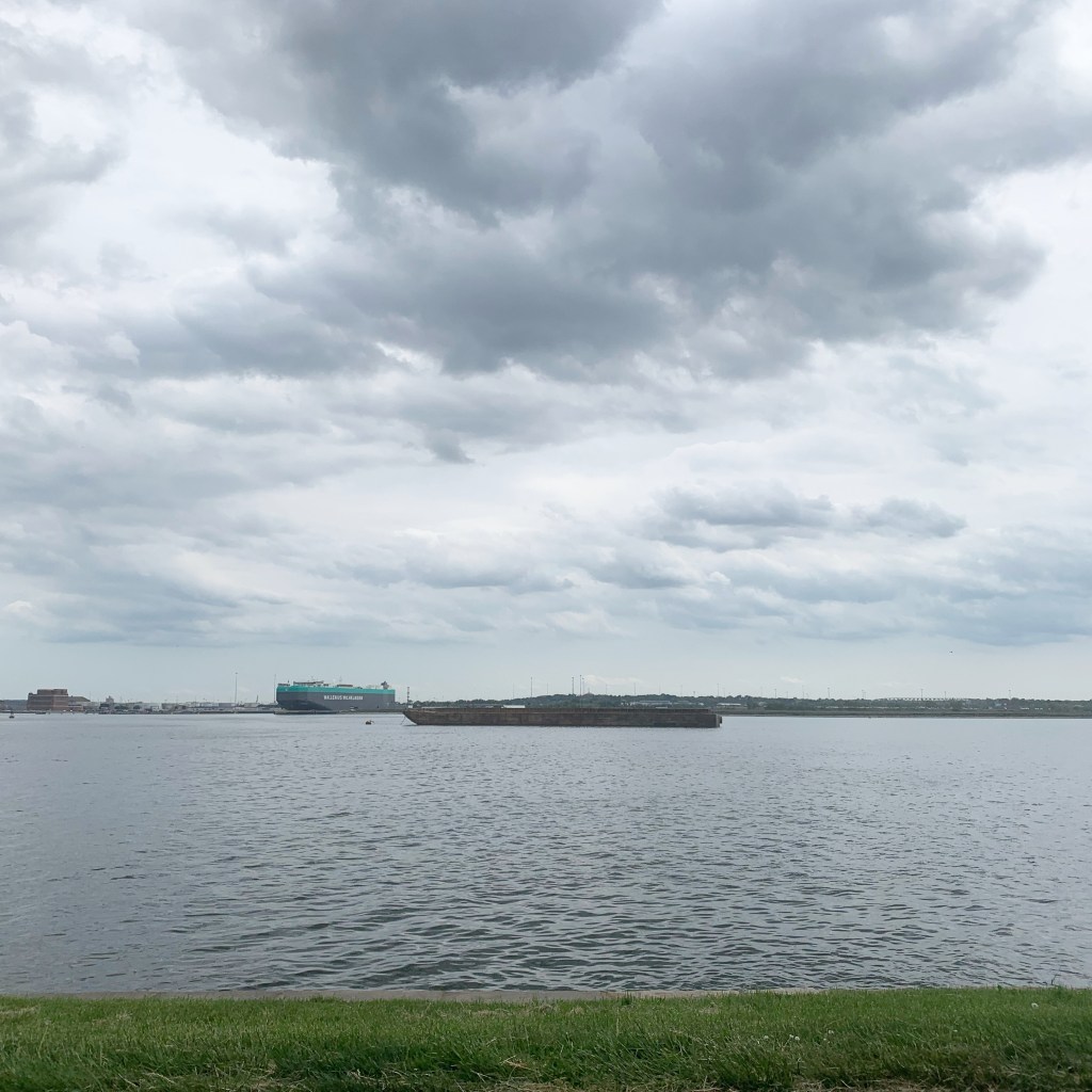 Gray and cloudy skies in the background, dark water in the foreground, and two ships on the water.