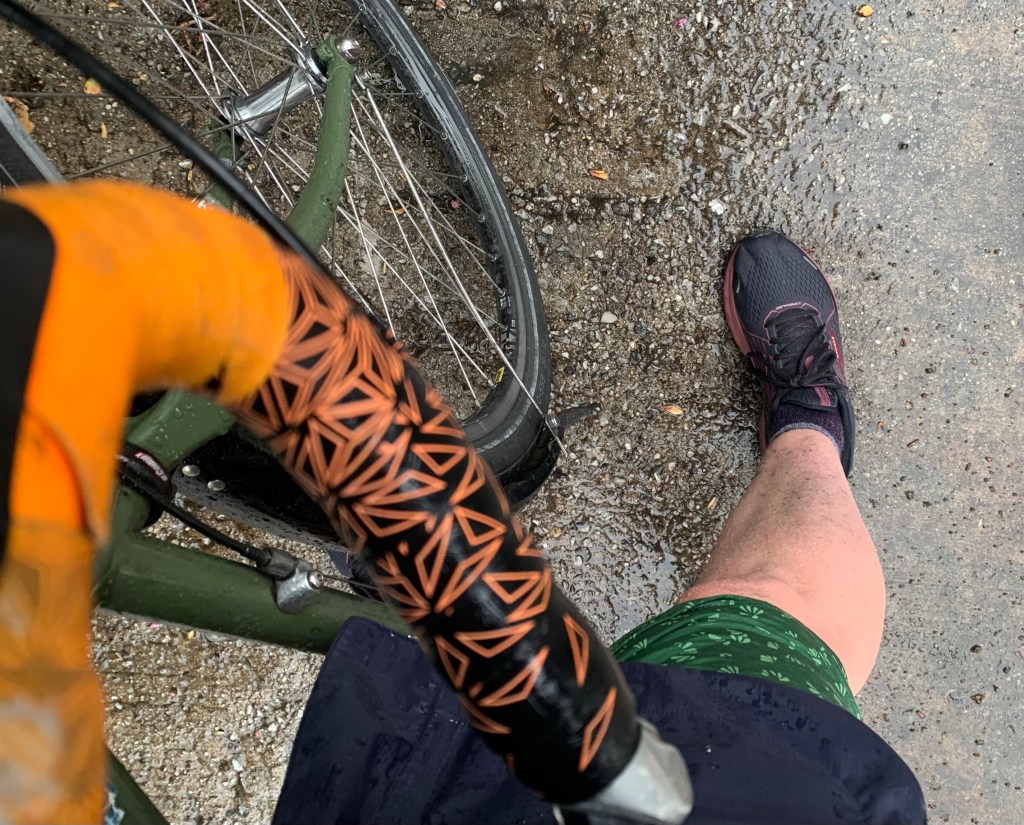 Looking down at a a bike handlebar and my wet skirt and dirty leg from biking in the rain.
