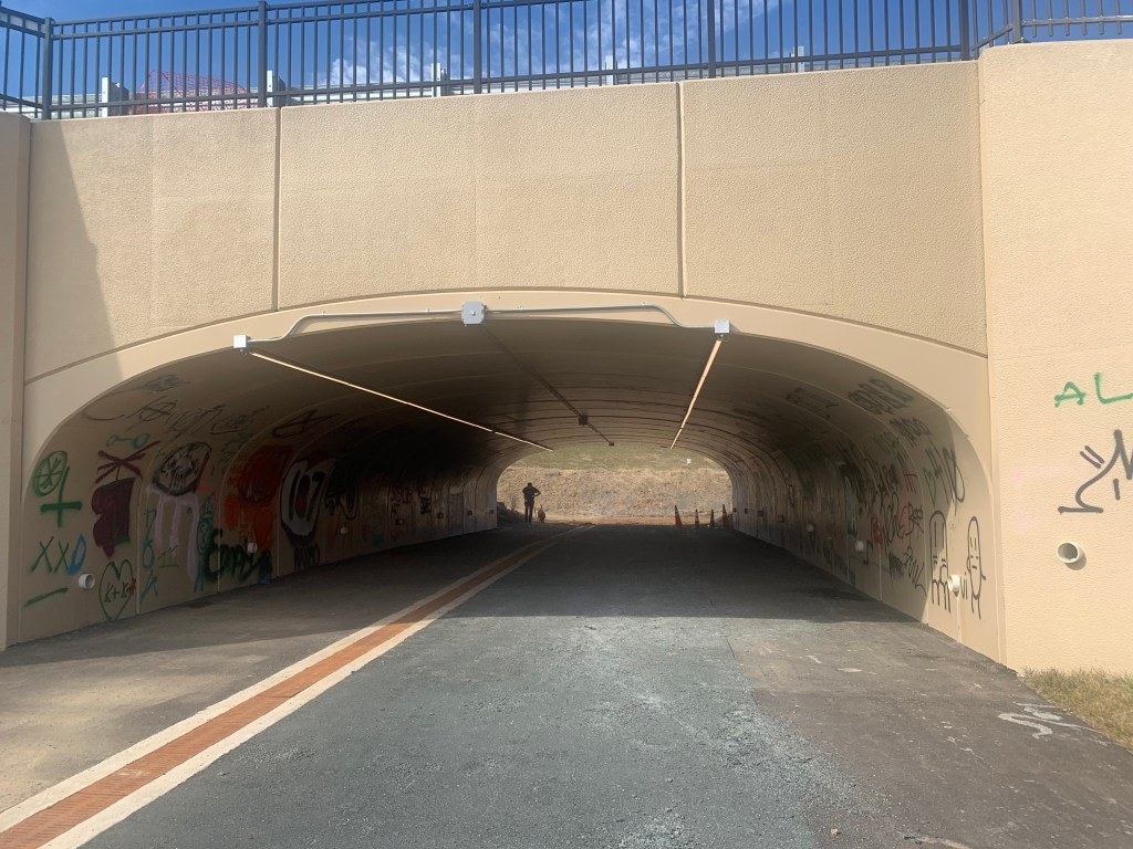 Looking down a tunnel under a bridge that dead ends into nothing.